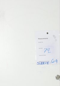 Metka z wymiarami na białym tle. Zawiera rozmiar ramion, całkowitą długość (72) oraz długość rękawa (69) napisaną niebieskim tuszem.