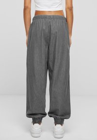 Gray wide-leg pants with an elastic waistband, featuring elastic cuffs at the ankles. Worn with white sneakers.