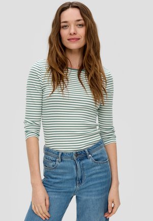 Haut à manches longues rayé en vert clair et blanc associé à un jean bleu taille haute. Le haut présente un col rond et une coupe ajustée.