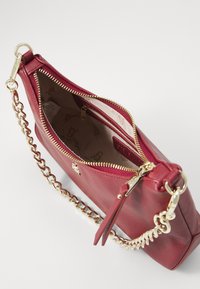 Red leather handbag with a gold zipper, chain strap, and a textured finish. The interior is lined with a patterned beige material.