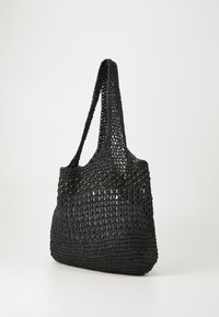 Borsa tote nera intrecciata con un design a trama aperta, dotata di manici lunghi e una superficie texturizzata, accentuata da perline scure lungo il bordo superiore.