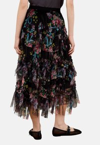 Czarna spódnica maxi z tiulu z warstwami falbanek i kwiatowym wzorem, w którym znajdują się kolorowe kwiaty. Projekt zawiera miękką elastyczną gumkę w talii.