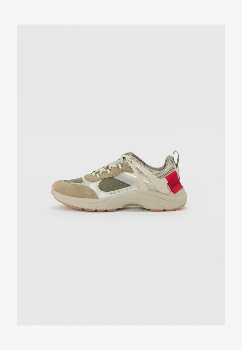 Sportos sneaker, khaki nubuk és hálós felsőrésszel, fényvisszaverő részletekkel, bézs középsole-val és piros logóval a saroknál.