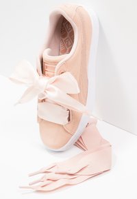 Helle rosa Sneaker aus Wildleder und Mesh, ausgestattet mit einer großen Satinschleife und einem Klettverschlussriemen, mit einer weißen Gummisohle und flachen Schnürsenkeln.