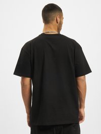 Sort bomulds t-shirt med løs pasform, korte ærmer og rund halsudskæring. Har en glat tekstur og enkel rygdesign.