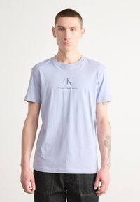 Camiseta de algodón azul claro con mangas cortas y cuello redondo, que presenta un pequeño logo de Calvin Klein Jeans impreso en el frente.