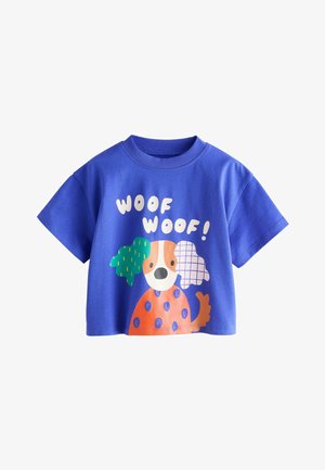 Blauw katoenen t-shirt met een speelse hondenafbeelding met groene en gemêleerde accenten. Tekst luidt "WOOF WOOF!" in wit. Korte mouwen.