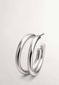 Pendientes de aro de plata con un acabado pulido. Presentan un diseño de doble lazo, textura suave y una forma abierta y ligera.