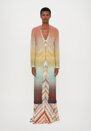 Long, knitted dress featuring a gradient from orange to turquoise, with a repeating geometric pattern and a deep V-neckline.