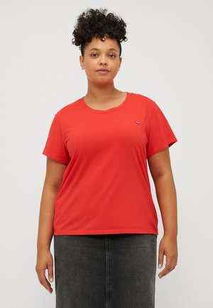 Red cotton t-shirt with short sleeves and a round neckline; features a small logo on the left chest; paired with a dark gray skirt.