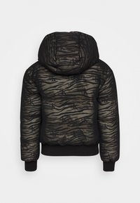 Svart vadderad jacka med tigerstripe-mönster, logotypdetaljer, huva och ribbade muddar. Texturerat tyg med en glänsande yta.