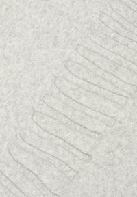 Tissu tricoté gris clair avec des fentes découpées le long d'un bord, offrant texture et contraste à la surface lisse de fond.