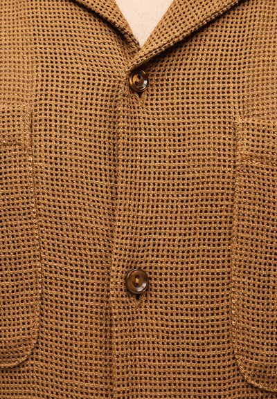 Καφέ σακάκι με ύφανση τύπου βάφλας με δύο κουμπιά και δύο μπροστινές τσέπες, που δείχνει λεπτομερή υφή υφάσματος και γιακά.