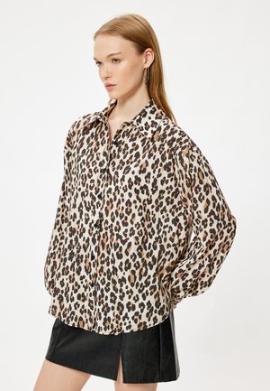 Een shirt met luipaardprint, gemaakt van lichtgewicht stof, met een relaxed fit, knoopsluiting aan de voorkant en een klassieke kraag. Combinatie met een zwarte leren minirok.