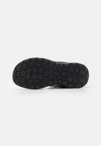 Suela de goma negra con patrones de tracción circulares; sección del talón reforzada y marca Geox en el lateral. Diseñada para un agarre sólido y comodidad.