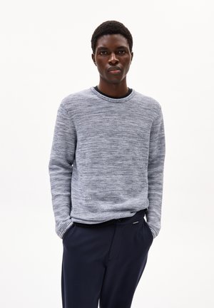 Pull bleu clair à col rond avec un motif de tricot texturé, associé à un pantalon marine. Le pull dispose de manches longues et d'une coupe décontractée.