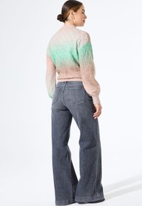 Gebreide trui met pastelgradiënt van roze naar groen, met een gestructureerd ruitpatroon. In combinatie met donkere, wijde denim jeans.