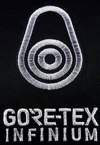 Zwarte stof met witte geborduurde logo met een druppelvorm en concentrische cirkels boven de tekst "GORE-TEX INFINIUM".