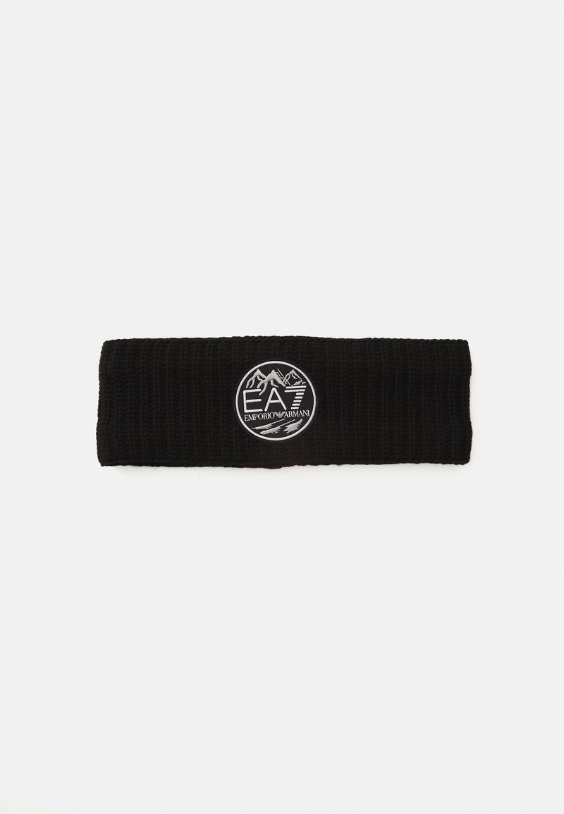 Un bandeau en tricot noir avec un patch circulaire blanc portant le logo Emporio Armani EA7 au centre, représentant des montagnes et du texte.