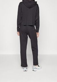 Black ribbed cropped hoodie with a hood, paired with matching black sweatpants. Footwear features a multicolored patterned design.