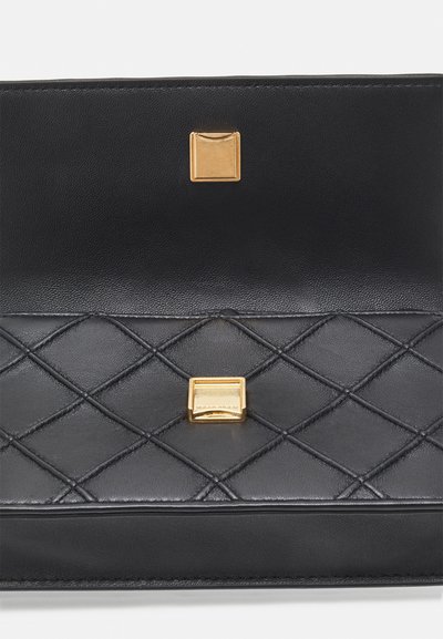 Black leather handbag with quilted pattern, featuring gold hardware accents and a smooth texture. Closure has a square magnetic snap.