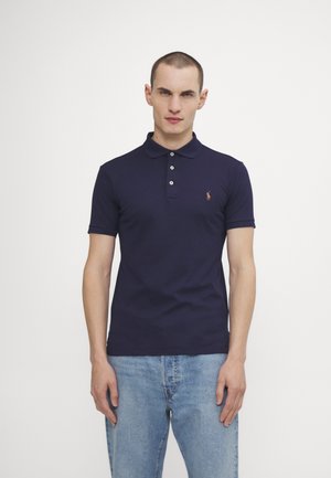 Marineblauwe polo met een drieknops knoopsluiting en korte mouwen; bevat een klein geborduurd logo op de linkerkant van de borst; zacht katoen.