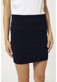 Námořnicky modrá strečová mini sukně se širokým, překládaným pasem. Hladká textura, přiléhavý design a žádné viditelné vzory ani akcenty.