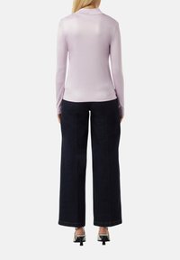 Lila Langarmoberteil mit hohem Kragen, kombiniert mit dunkelblauem, weit geschnittenem Hosen. Das Outfit hat eine glatte Textur und ein elegantes Design.