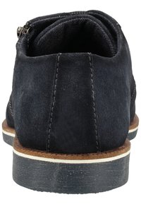 Chaussure habillée pour homme en daim bleu foncé avec couture verticale cousue sur le talon, bordure marron, bande blanche sur la semelle intermédiaire et semelle extérieure en caoutchouc noir.