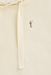 Ljusbeige hoodie med texturerad yta, med en liten brun broderad figur på vänster bröst och en huva med dragsko.