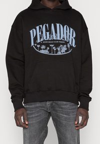 Schwarzer Hoodie mit einem großen blauen Grafikdruck, auf dem "PEGADOR" und "MIAMI BEACH CLUB RESORT" steht, sowie einer vorderen Kängurutasche.