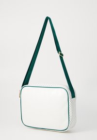 White synthetic bag with a smooth front, perforated sides, green accents, and an adjustable green strap. Zipper closure at the top.