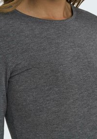 Grey long-sleeve shirt made of soft, textured fabric with a round neckline. Features a fitted design, showcasing a smooth finish.