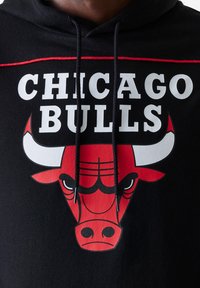 Manta preta com um grande logótipo vermelho e branco dos Chicago Bulls, apresentando um gráfico de uma cabeça de touro e o texto audacioso em branco "CHICAGO BULLS" acima.
