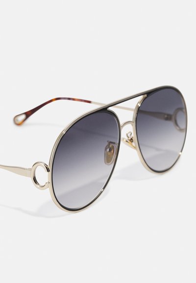 Óculos de sol aviador dourados com lentes cinzentas em degradé. Inclui armações redondas e pontas das hastes em tartaruga castanha com acentos circulares.