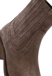 Botín de ante marrón con detalles de brogue, panel lateral elástico y tacón de madera apilada.