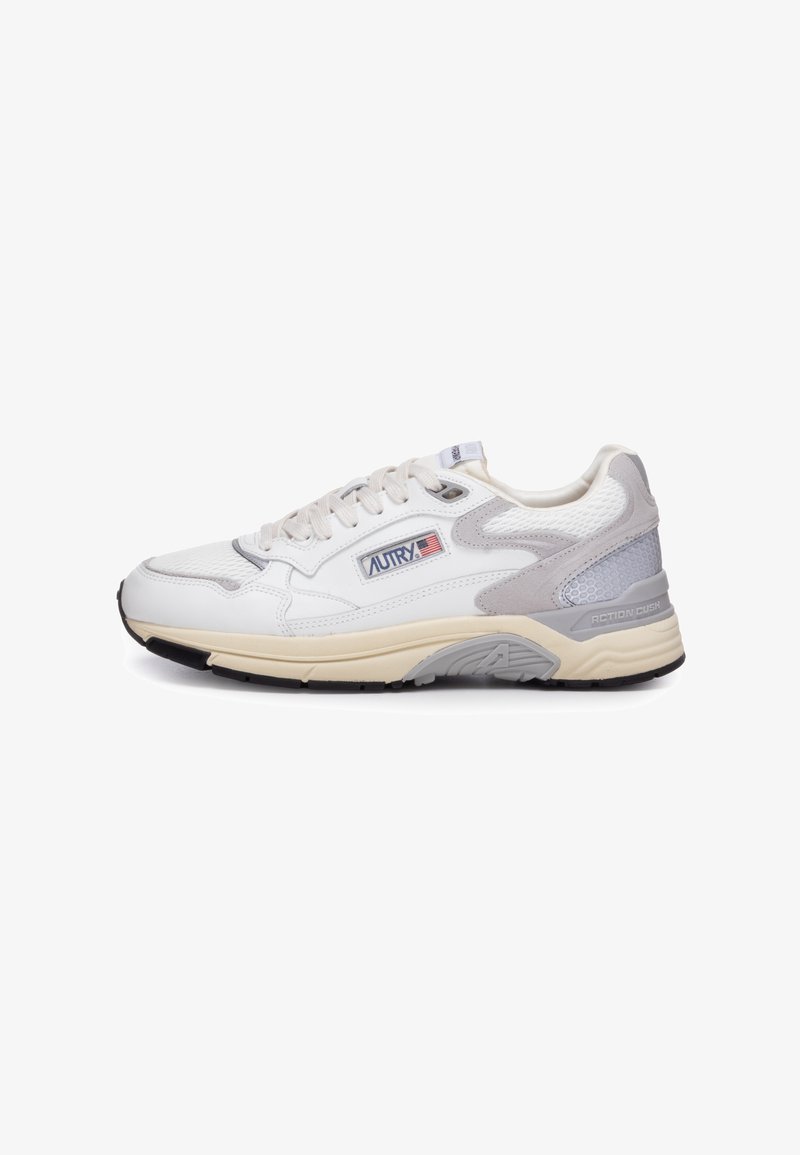Zapatilla deportiva blanca con materiales de malla y cuero, acentos en gris claro, suela texturizada y logotipo "AUTRY" en el lateral.