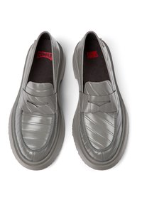 Grijze synthetische instapschoenen met een geribbeld patroon aan de voorkant, voorzien van een band over de bovenkant en een dikke rubberen zool. Rode accenten aan de binnenkant.