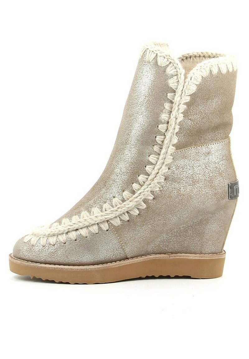 Wedge enklaars in metallic zilver met een gestructureerde afwerking, decoratieve witte stiksels langs de naden en een rubberen zool.