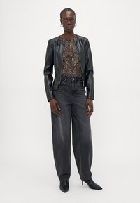 Black leather jacket with a zip front, paired with a leopard print top and gray wide-leg jeans. Model wears black pointed ankle boots.