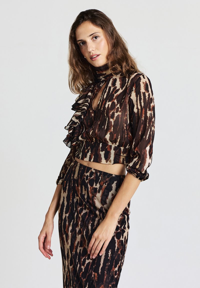 Completo composto da top corto e gonna in tessuto trasparente con stampa leopardata marrone e beige, caratterizzato da dettagli arricciati, maniche lunghe e scollo a goccia.