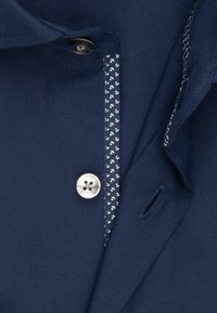 Námořnická košile s jemným bílým paisley vzorem uvnitř légy a stříbrným knoflíkem. Hladká textura s pevným límečkem.