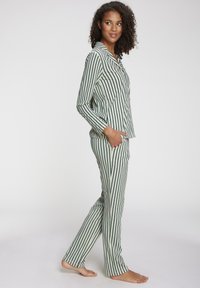 Green and white striped pajama set with long sleeves and pants. Soft fabric, button-up shirt, and side pockets.