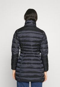 Sort puffet jakke med høj krave, der har en quiltet design, lange ærmer og en tætsiddende silhuet, lavet af skinnende, vandafvisende materiale.