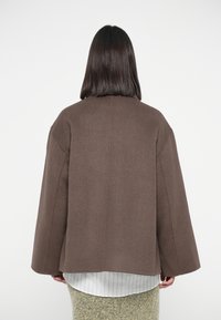 Brown wool-blend coat with a loose silhouette, dropped shoulders, and wide sleeves, featuring a clean back design.