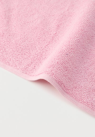 Απαλό ροζ πετσέτα από περκάλι με εμφανή υφή βρόχων σε λευκή επιφάνεια.