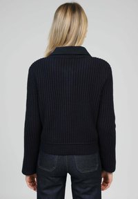 Pull en maille côtelée bleu marine avec col, manches longues et coupe courte. Tissu texturé et couleur unie offrant un design minimaliste.