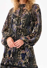Robe à manches longues avec un col montant, présentant un motif cachemire noir, bleu et or, des détails à volants et un tissu texturé.