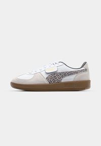 Baskets Puma avec une tige blanche et des accents en cuir suédé, un panneau latéral à imprimé léopard et une semelle en caoutchouc brun texturé.
