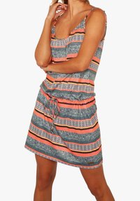 Robe à motifs avec bretelles spaghetti ; présente des rayures grises, orange et noires, une taille avec cordon de serrage et un motif de feuilles ludique.